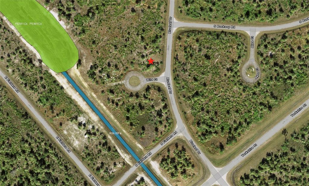 This is an aerial map showing a vacant lot marked with a red star — WILD COURT, NORTH PORT, FL