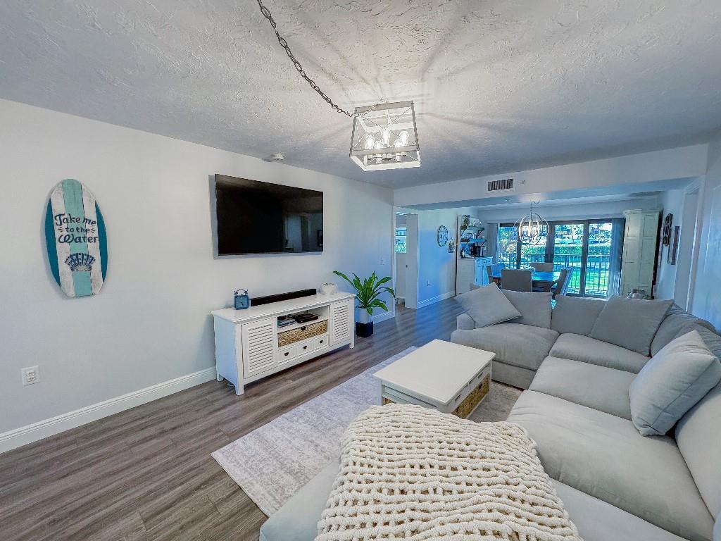 A living room features a sectional sofa, a white media console, and a surfboard wall decoration — 901 Seafarer Circle # 101, Jupiter FL 33477, JUPITER, FL