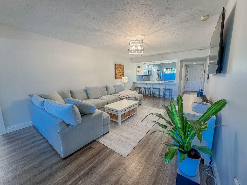A living room with a large sectional sofa, coffee table, and open kitchen with bar seating — 901 Seafarer Circle # 101, Jupiter FL 33477, JUPITER, FL