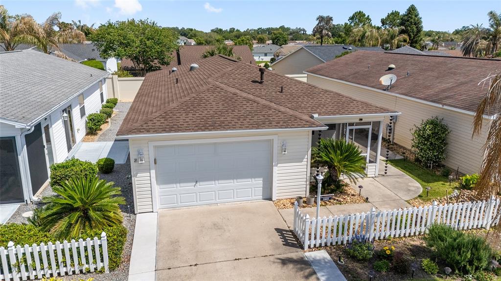 A single-story house exterior features a white garage, a screened porch, and a landscaped yard — 2403 BATON PLACE, THE VILLAGES, FL
