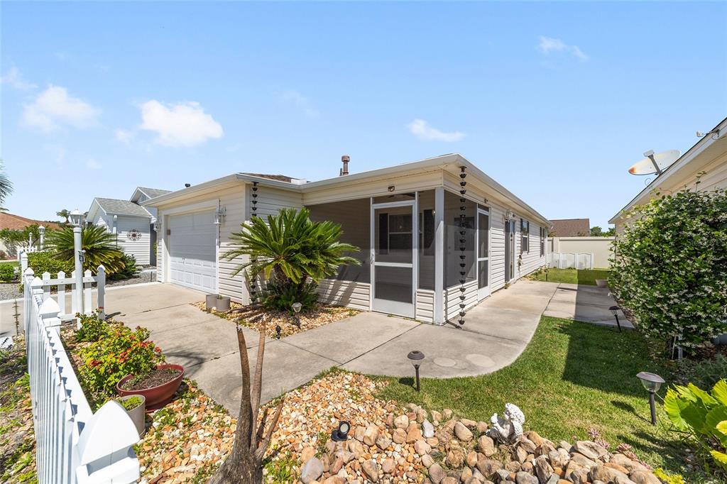 A single-story house with a white picket fence, a garage, and a screened-in front porch — 2403 BATON PLACE, THE VILLAGES, FL