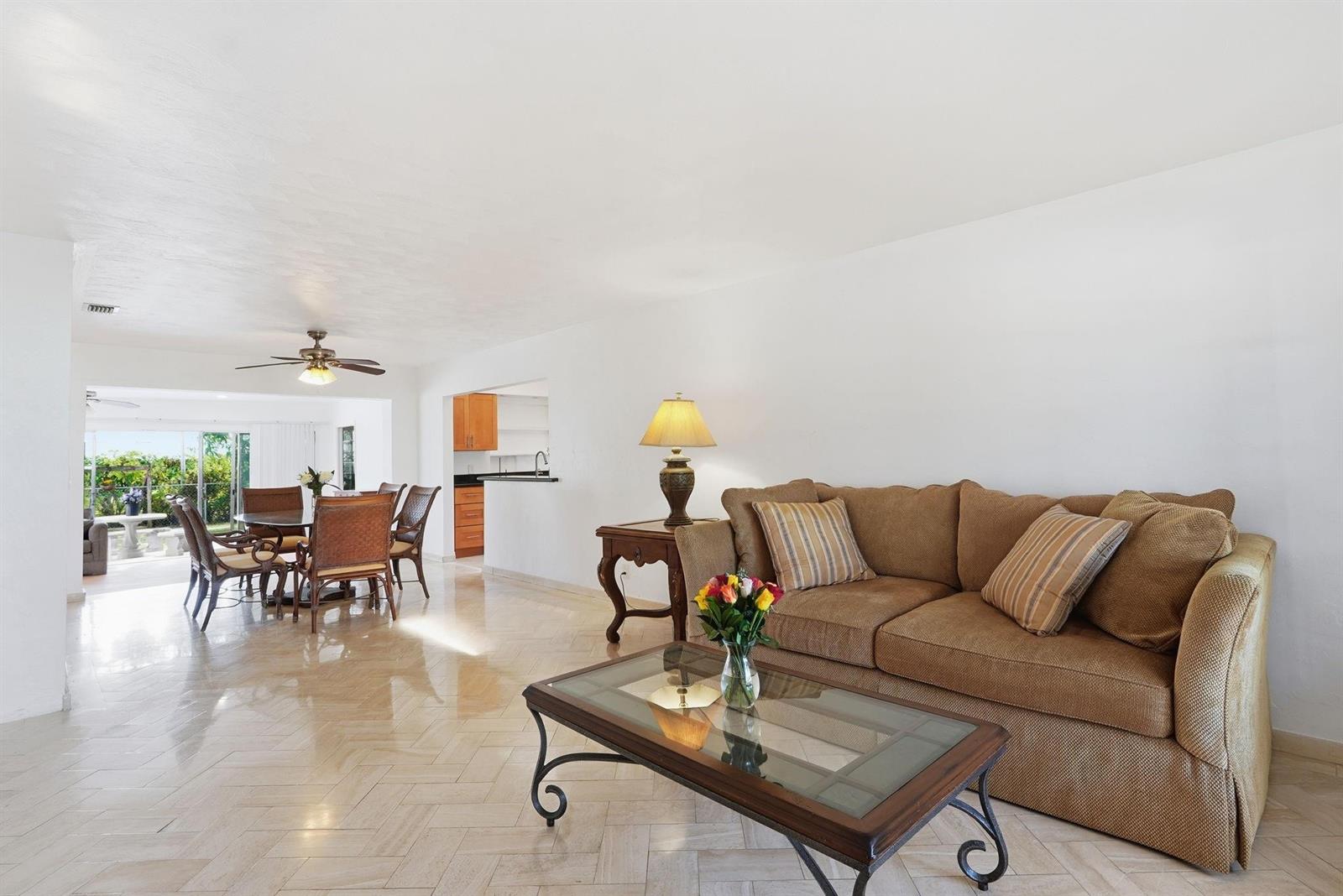 A living room with a brown sofa, glass coffee table, and adjacent dining area — 218 SE 3rd Terrace, Dania Beach FL 33004, DANIA BEACH, FL