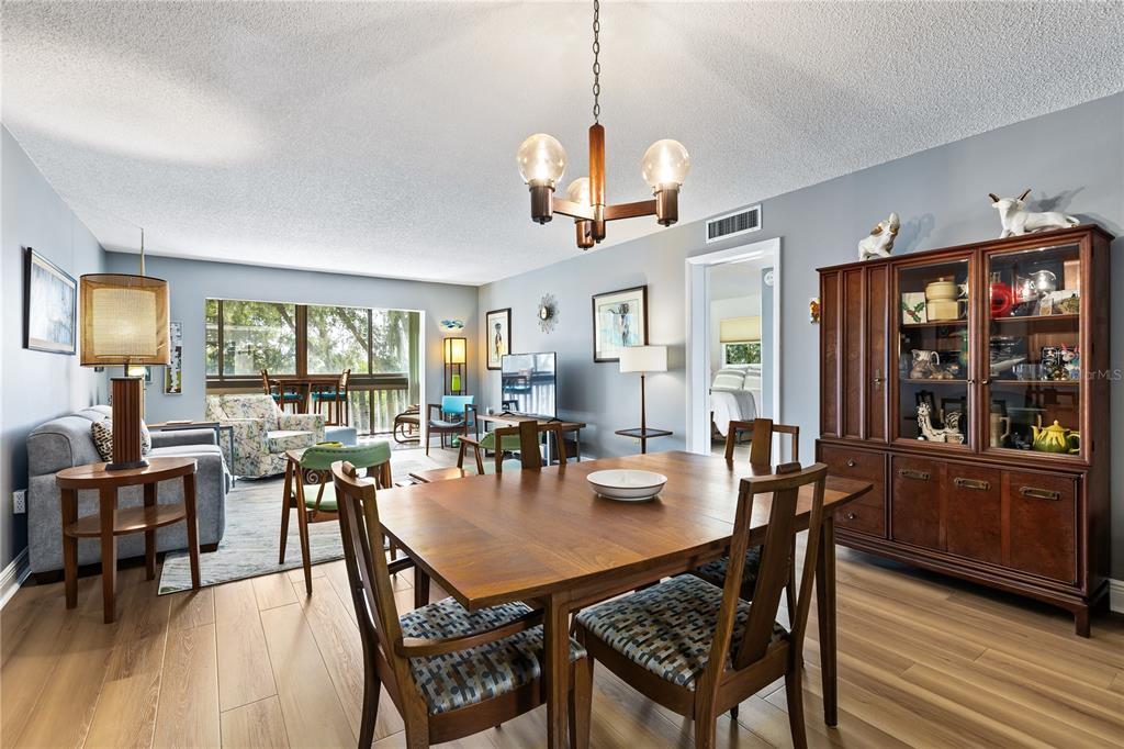 A dining area with a wooden table and hutch opens into a living room space — 601 N MCDONALD STREET UNIT 310, MOUNT DORA, FL