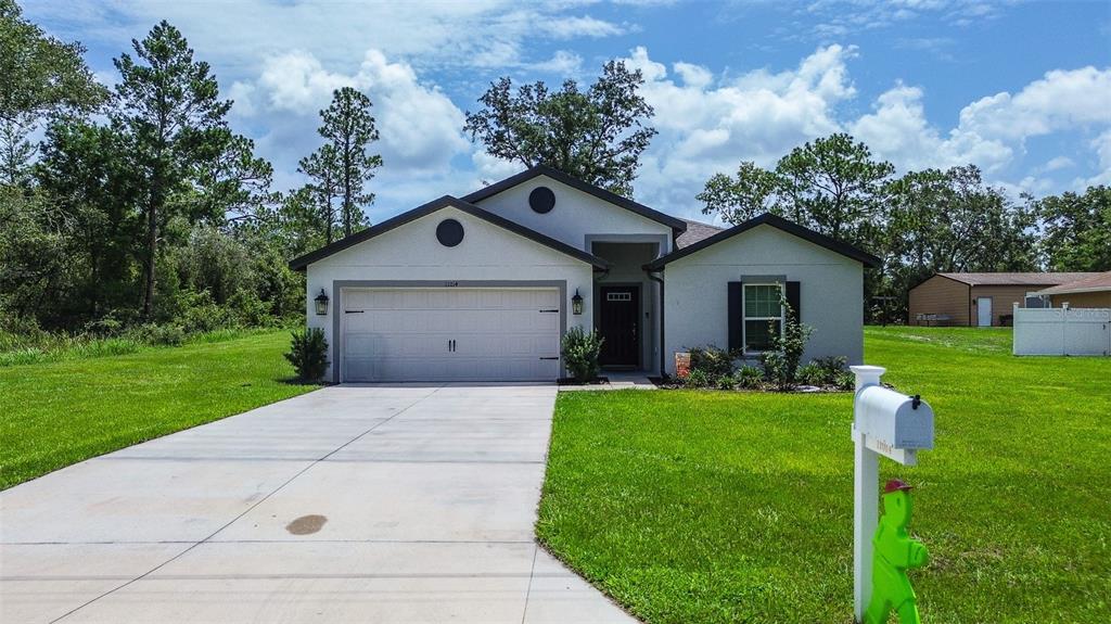 A single-story house with a white stucco exterior, a two-car garage, and a concrete driveway — 11014 GOLDEN WARBLER, BROOKSVILLE, FL