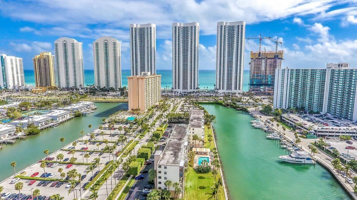 An aerial view shows high-rise residential buildings along a canal with boats and parking lots — SUNNY ISLES BEACH, FL