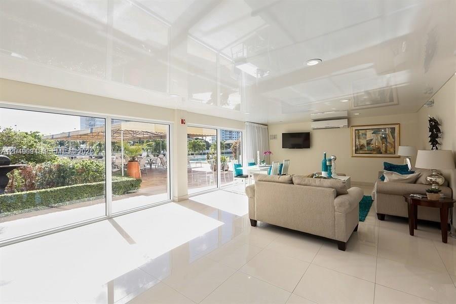 A bright living room features white tile floors, a glossy ceiling, and sliding glass doors — SUNNY ISLES BEACH, FL