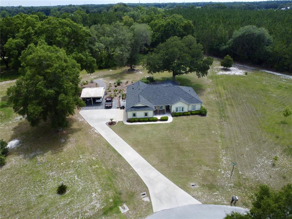 An aerial view shows a single-story house with a driveway and carport on a lot — 18450 NE 61ST LANE, WILLISTON, FL