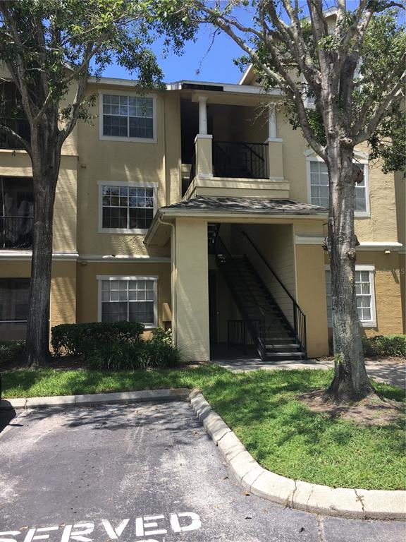 Exterior view of a multi-story apartment building with tan stucco siding and outdoor staircases — 2572 ROBERT TRENT JONES DRIVE UNIT 1215, ORLANDO, FL