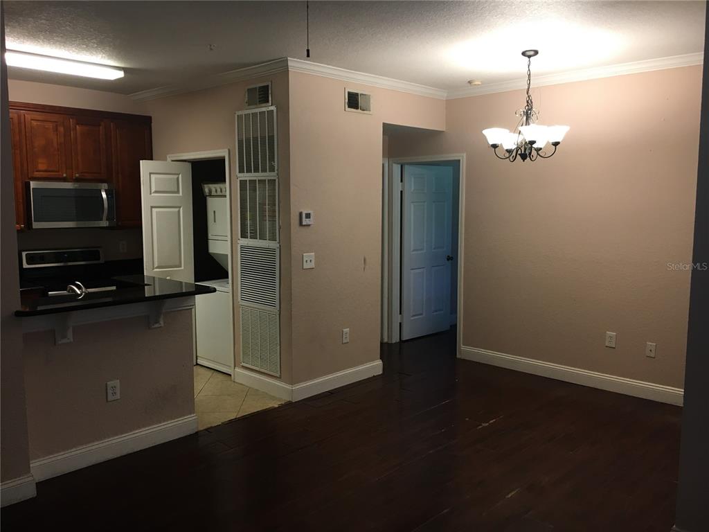 A view of a kitchen with dark cabinets and a dining area with a chandelier — 2572 ROBERT TRENT JONES DRIVE UNIT 1215, ORLANDO, FL