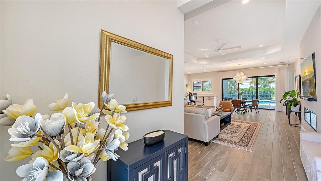 A foyer with a floral arrangement and mirror leads into an open-concept living and dining area — 2469 PARADISE PLUM DRIVE, SARASOTA, FL