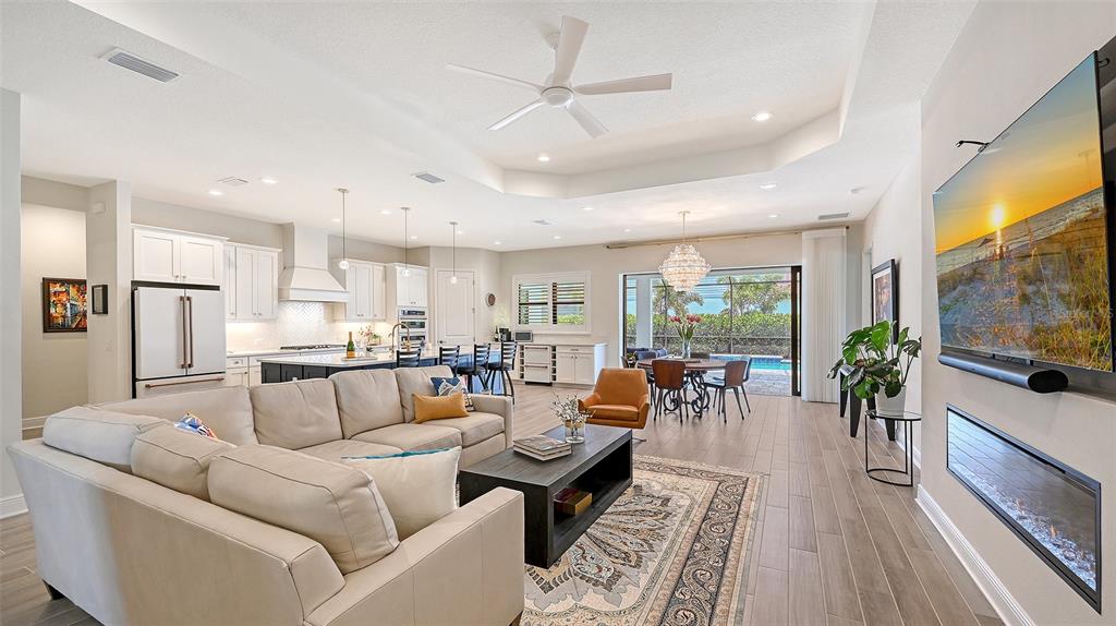 An open-concept living room and kitchen featuring a sectional sofa, fireplace, and pool view — 2469 PARADISE PLUM DRIVE, SARASOTA, FL