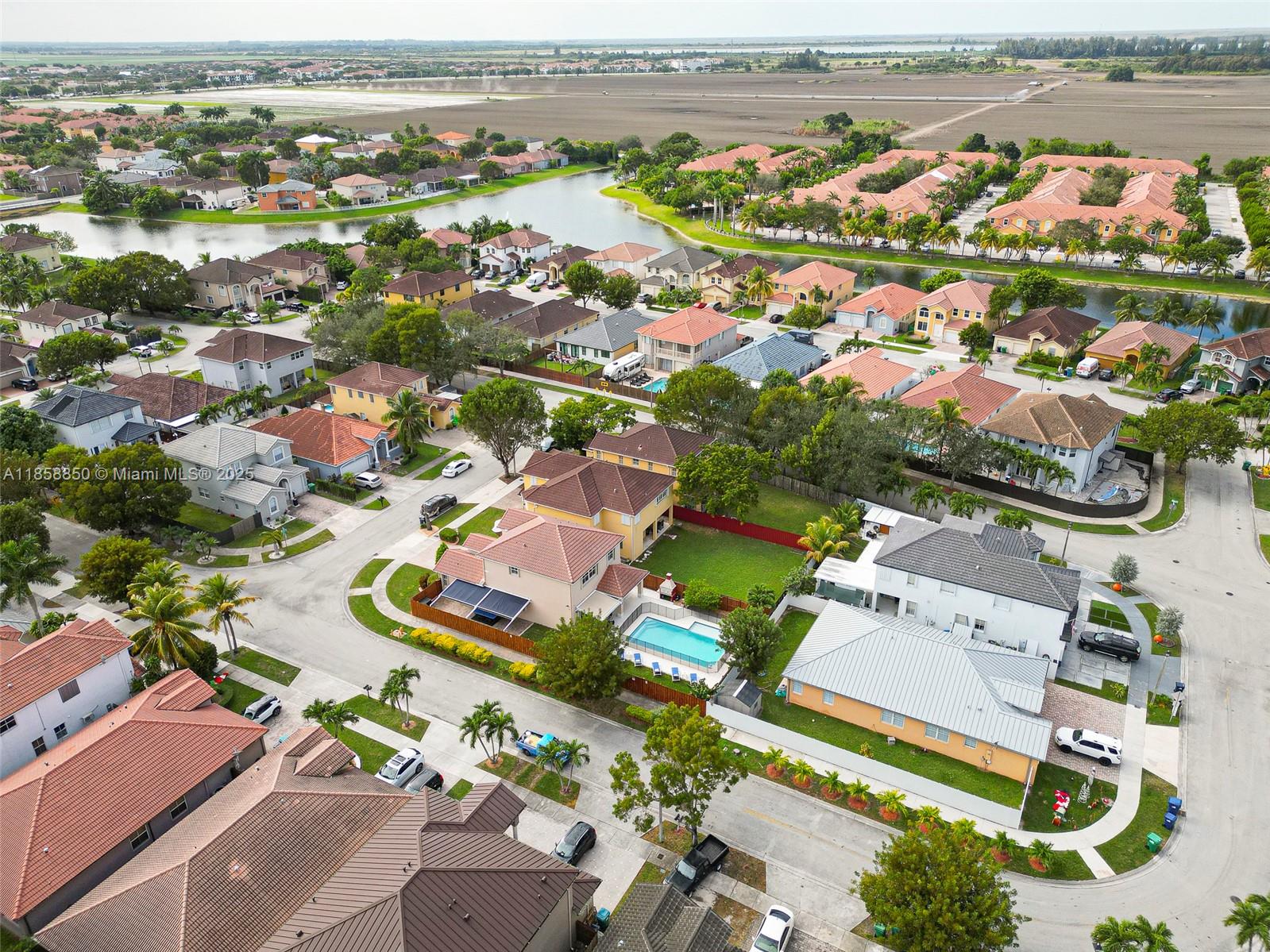 An aerial view shows a suburban neighborhood with houses, swimming pools, and a nearby lake — 16403 SW 79th Ln # 16403, Miami FL 33193, MIAMI, FL