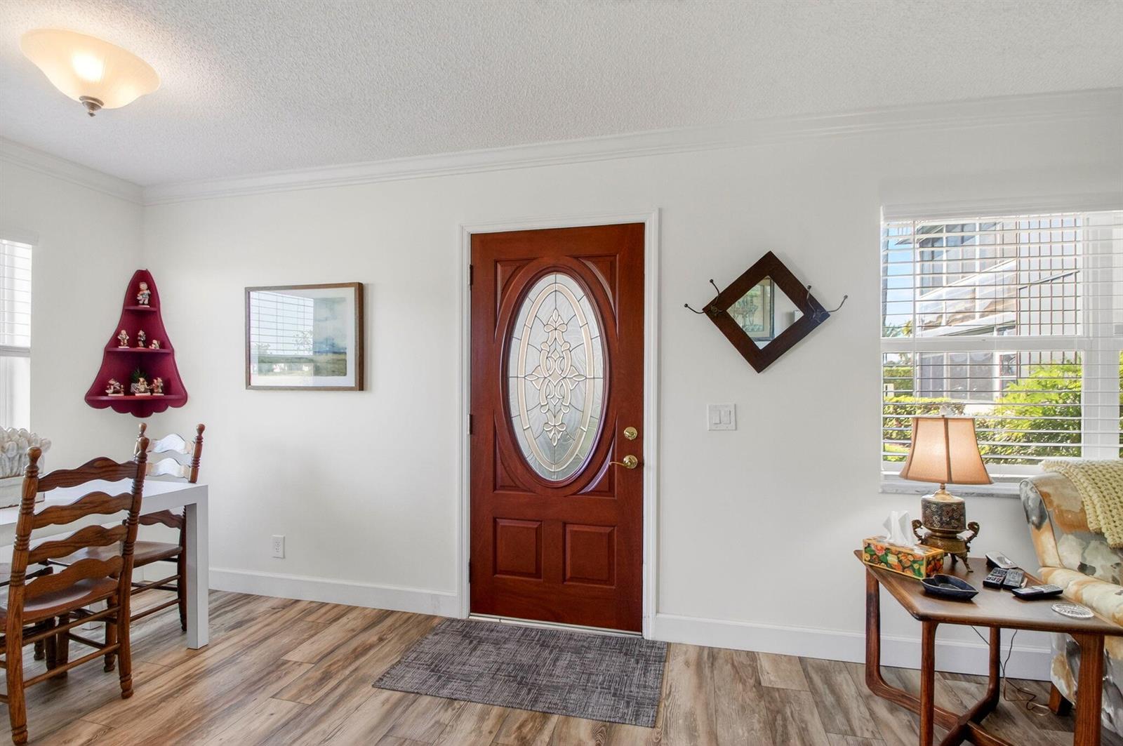 A dining area with wood-look flooring, a red corner shelf, and a front entry door — 3 Normandy A, Delray Beach FL 33484, DELRAY BEACH, FL