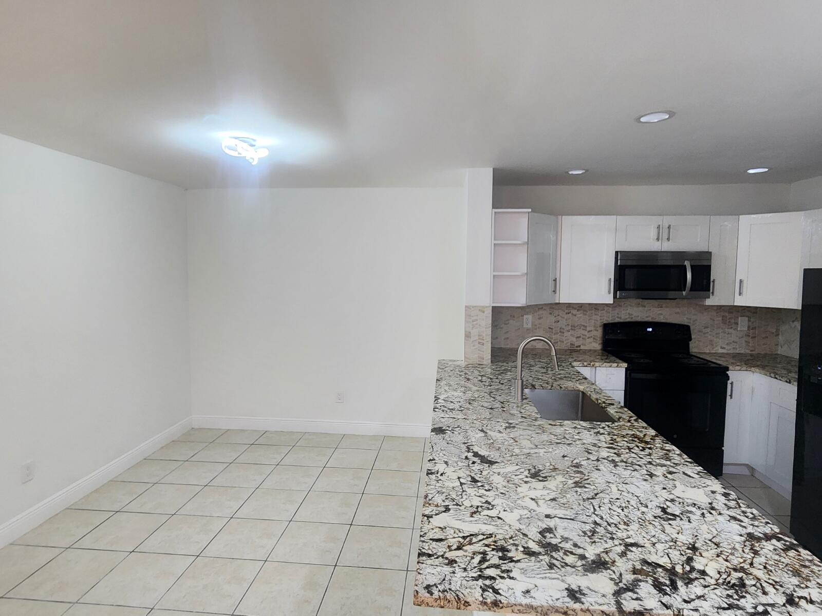 A kitchen with white cabinets, granite countertops, and a dining area with tile flooring — 6013 10th Avenue N # 208, FL 33463, FL