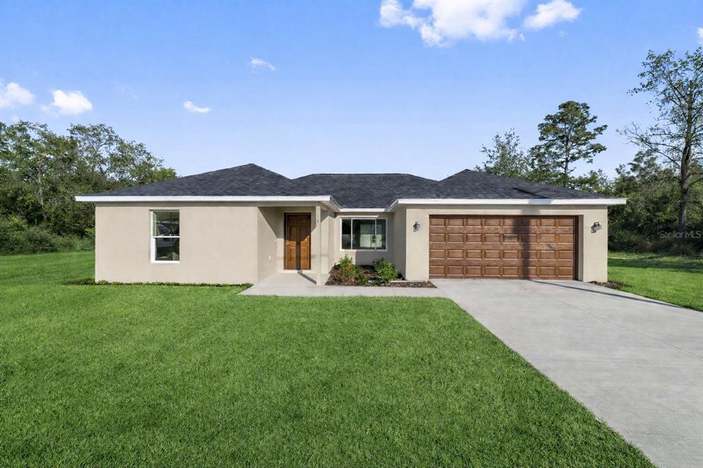 A single-story house with a beige stucco exterior, dark roof, and a two-car garage — 20 MALAUKA COURSE, OCKLAWAHA, FL