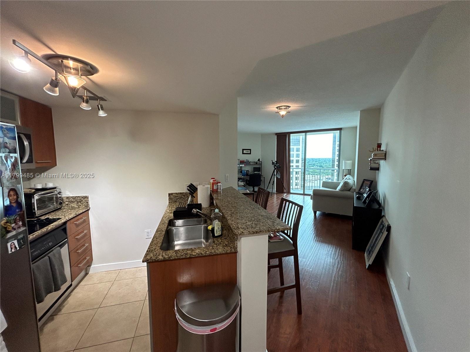 A kitchen with granite countertops and a breakfast bar opens into a living area — 9066 SW 73rd Ct # 1504, Miami FL 33156, MIAMI, FL