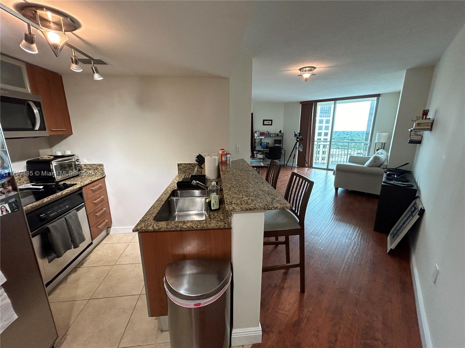 A kitchen with granite countertops and stainless steel appliances opens into a living area — 9066 SW 73rd Ct # 1504, Miami FL 33156, MIAMI, FL