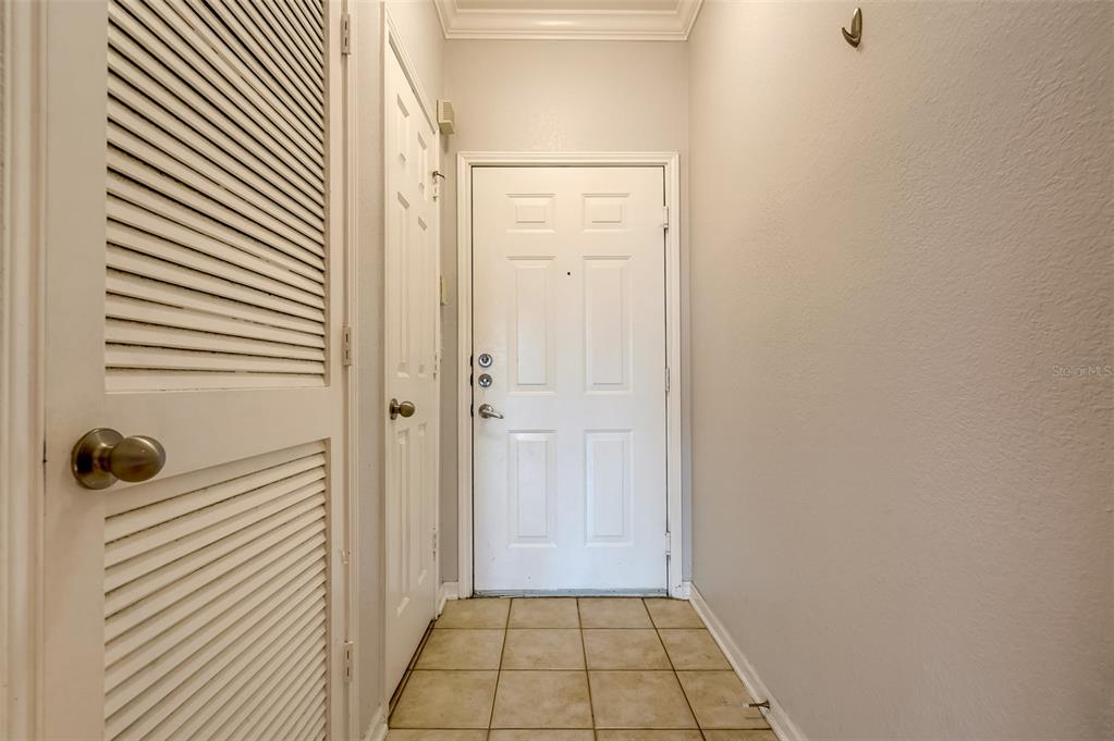 An entryway features a white front door, a louvered closet door, and tiled flooring — 1216 S MISSOURI AVENUE UNIT 311, CLEARWATER, FL