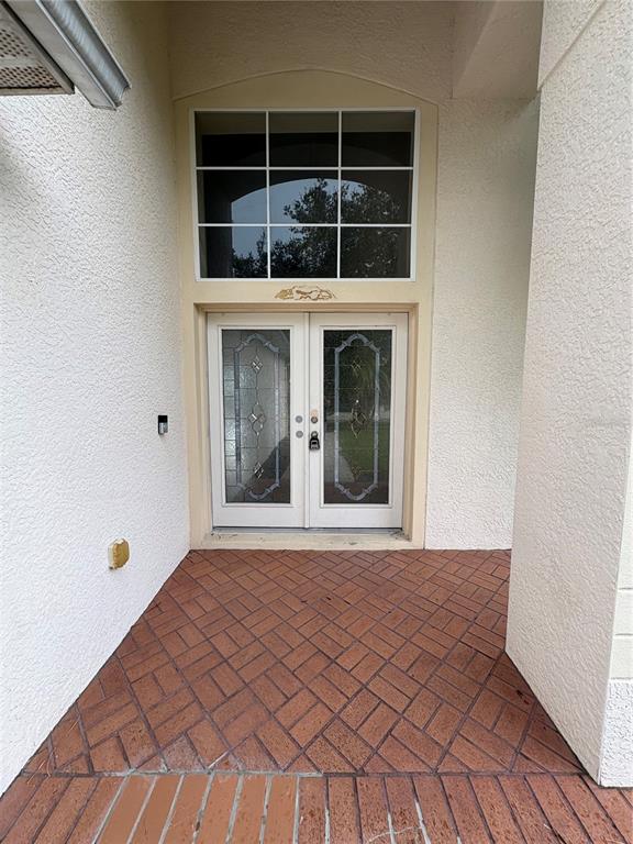 A front entryway features double glass-paneled doors, a transom window, and a brick-patterned porch floor — 2830 PANKAW LANE, VALRICO, FL