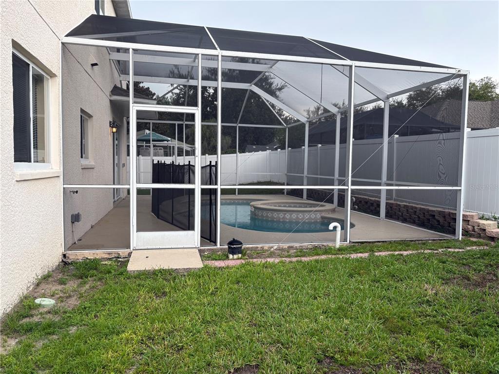 A screened-in pool and spa area is attached to the side of a stucco house — 2830 PANKAW LANE, VALRICO, FL