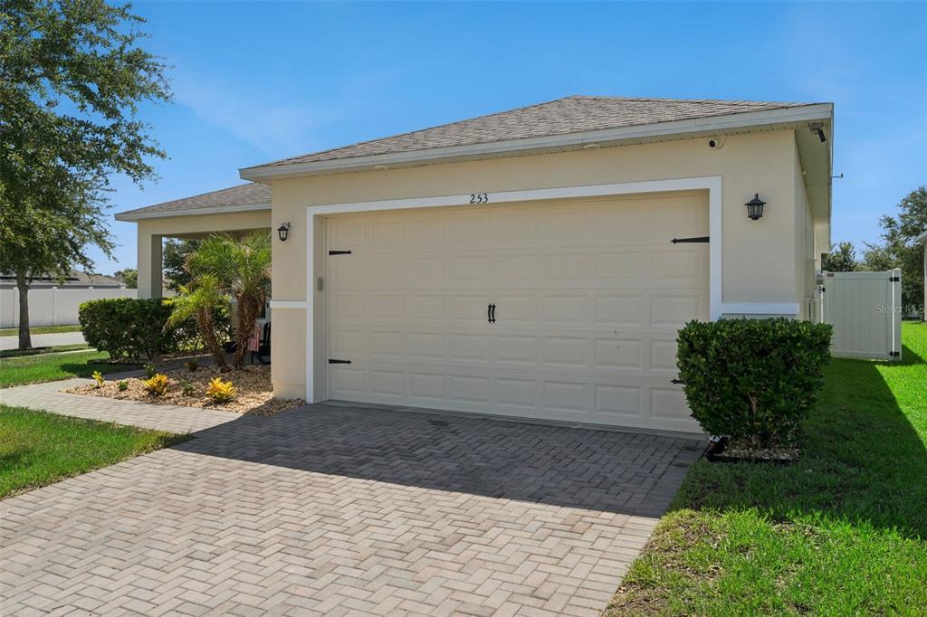 A beige house exterior features a paved driveway, a two-car garage, and landscaping — 253 SPARROW HAWK DRIVE, GROVELAND, FL