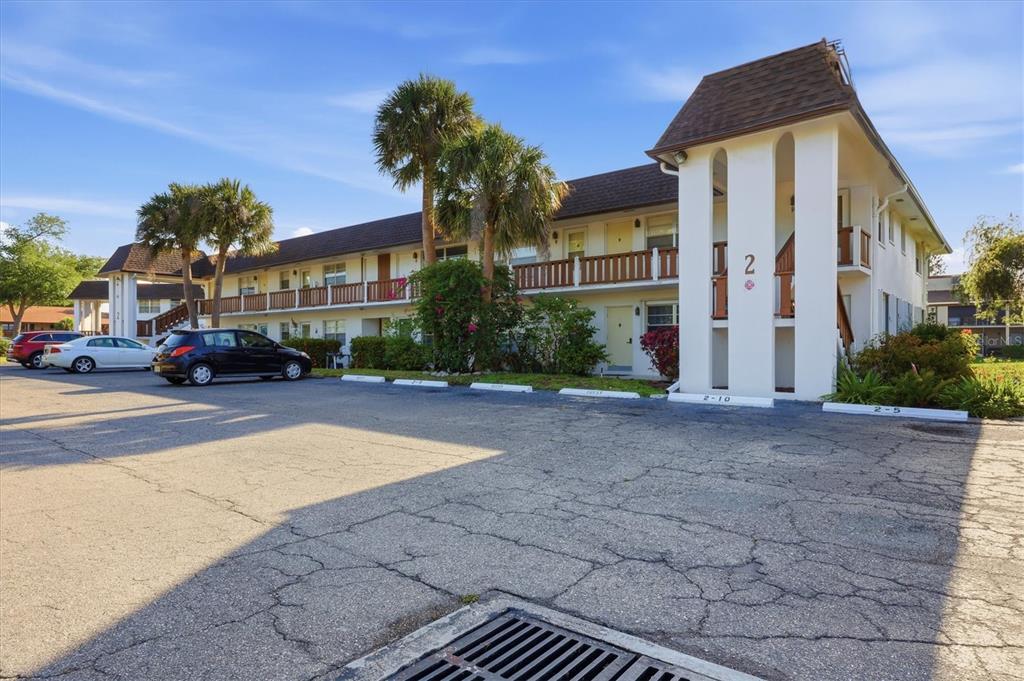 A two-story apartment building with a parking lot and palm trees in front — 2 QUAILS RUN BOULEVARD UNIT 2104, ENGLEWOOD, FL