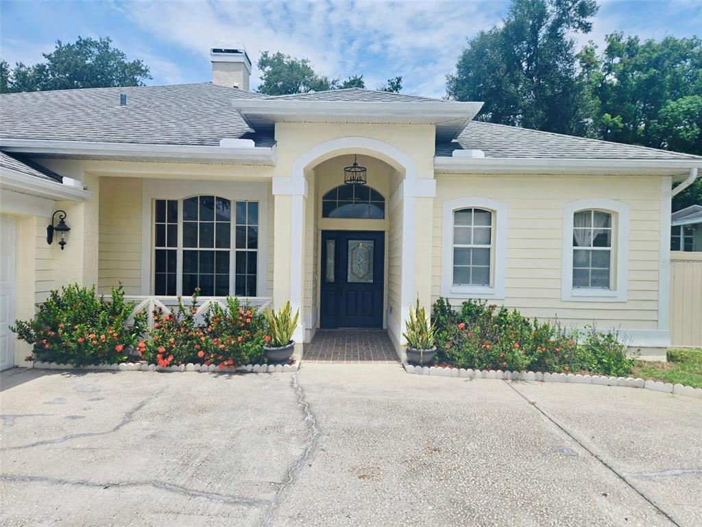 A single-story house with yellow siding, a dark front door, and a concrete driveway — 3029 MINUTEMAN LANE, BRANDON, FL