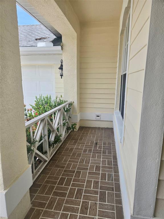A covered porch features a patterned brick floor, white lattice railing, and light-colored siding — 3029 MINUTEMAN LANE, BRANDON, FL