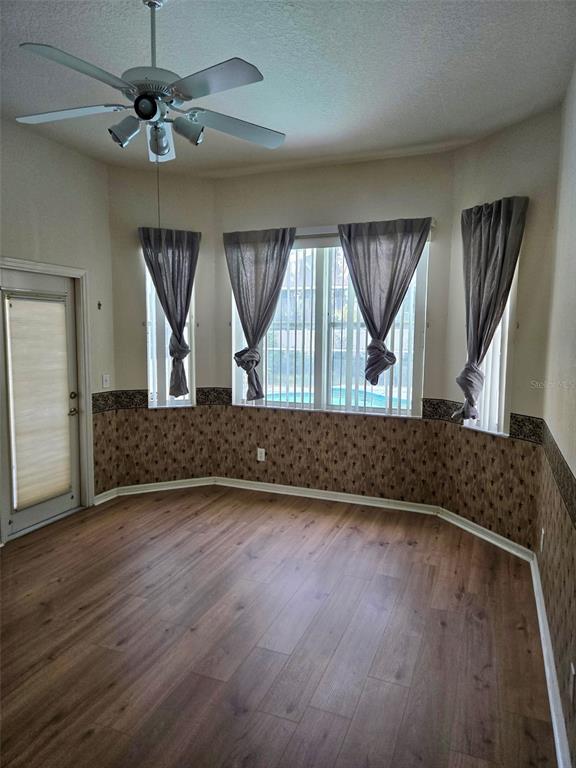 A room with wood-look flooring, a ceiling fan, and windows overlooking a swimming pool — 3029 MINUTEMAN LANE, BRANDON, FL