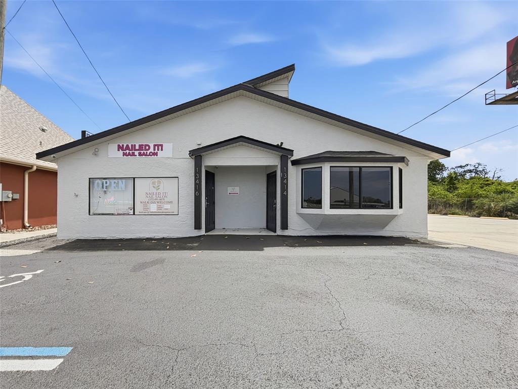 The exterior of a white commercial building with a nail salon sign and two entrances — 13414 US HIGHWAY 19, HUDSON, FL