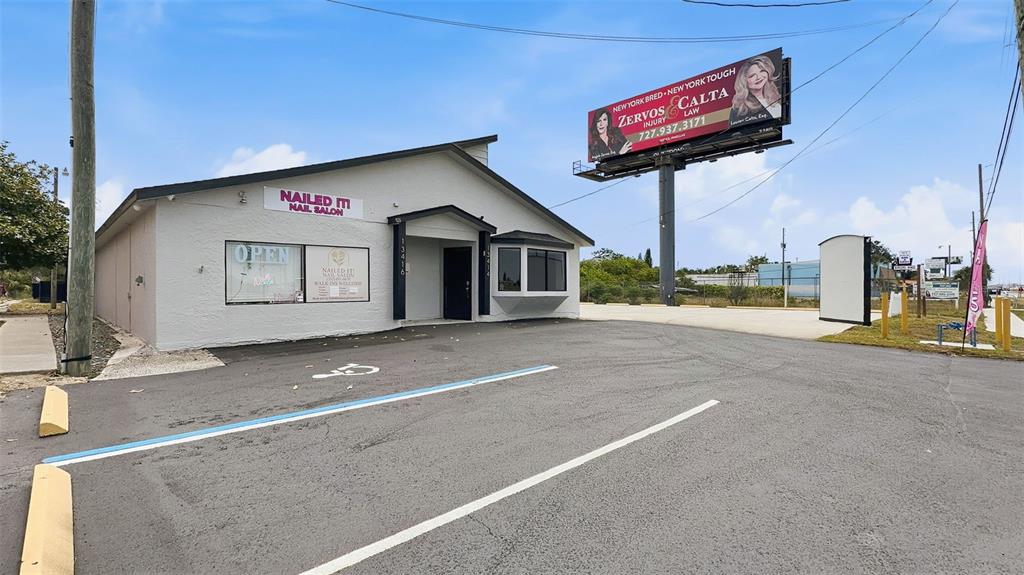 A single-story commercial building with a nail salon sign and an adjacent billboard — 13414 US HIGHWAY 19, HUDSON, FL