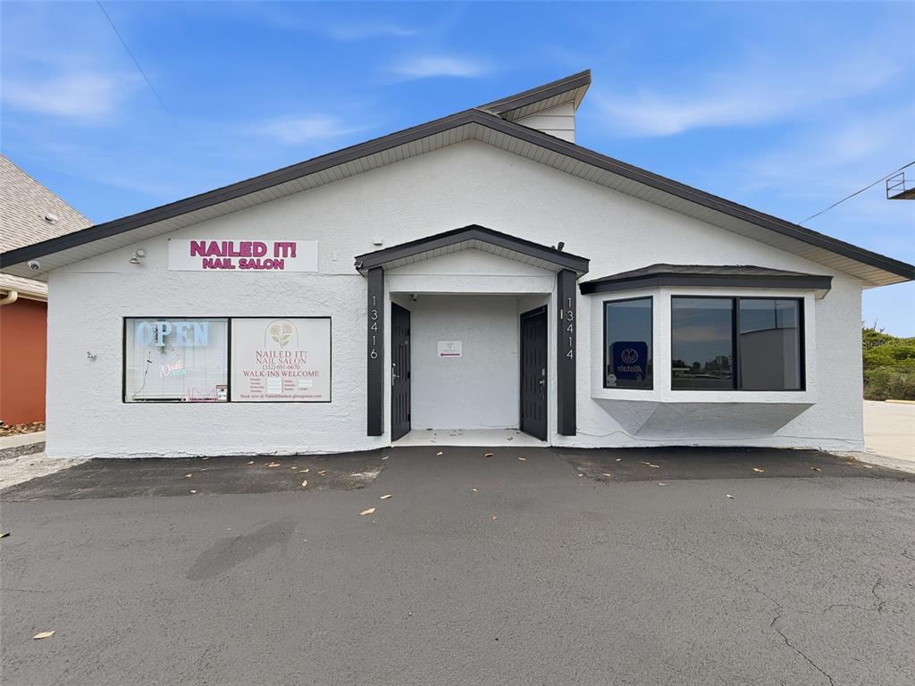 The exterior of a white commercial building features a nail salon sign and two entrances — 13414 US HIGHWAY 19, HUDSON, FL