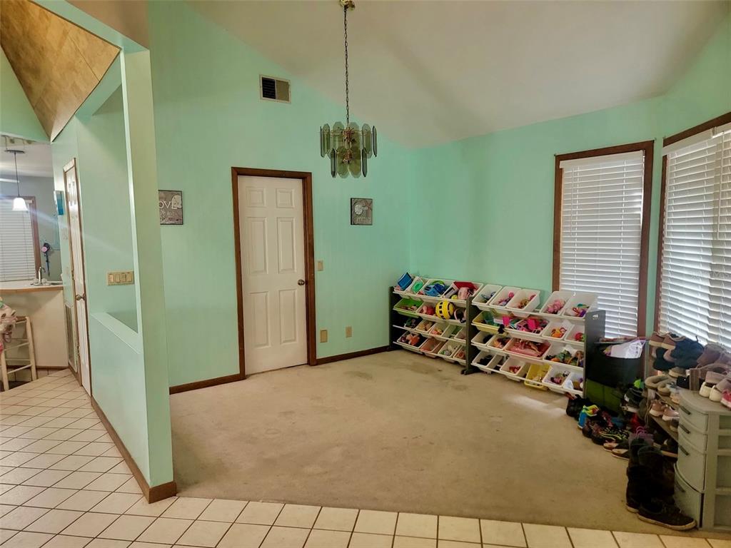 A carpeted room with light green walls, a chandelier, and open shelving for toy storage — 585 E FORESTHILL PLACE, HERNANDO, FL