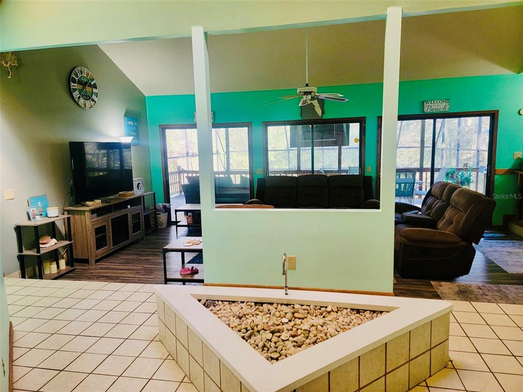 A living room features a central indoor rock planter, teal walls, and a screened-in porch — 585 E FORESTHILL PLACE, HERNANDO, FL