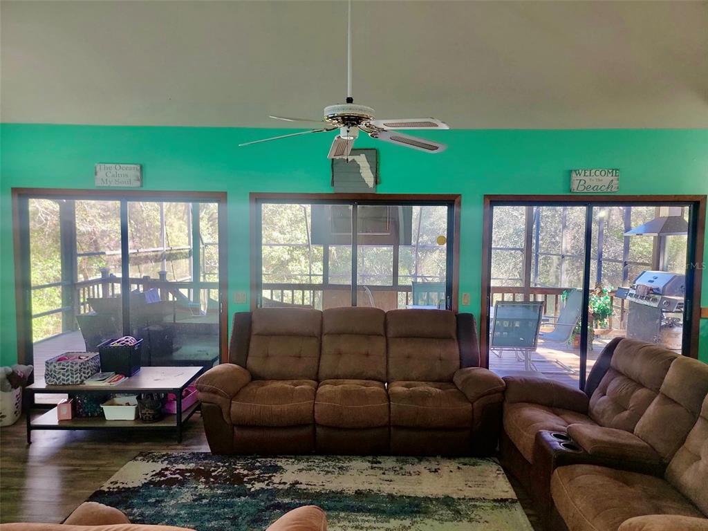 A living room features bright teal walls, a ceiling fan, and sliding glass doors — 585 E FORESTHILL PLACE, HERNANDO, FL