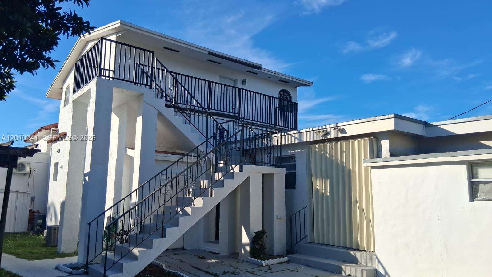 An exterior view of a two-story white building featuring an outdoor staircase and metal railings — 5629 SW 7th St, Miami FL 33134, MIAMI, FL