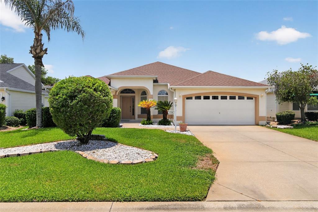 A single-story house with a white stucco exterior, brown roof, and a two-car garage — 17336 SE 80TH TURNBULL COURT, THE VILLAGES, FL
