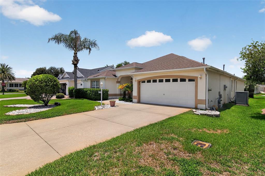 A single-story house with a beige exterior, a two-car garage, and a concrete driveway — 17336 SE 80TH TURNBULL COURT, THE VILLAGES, FL