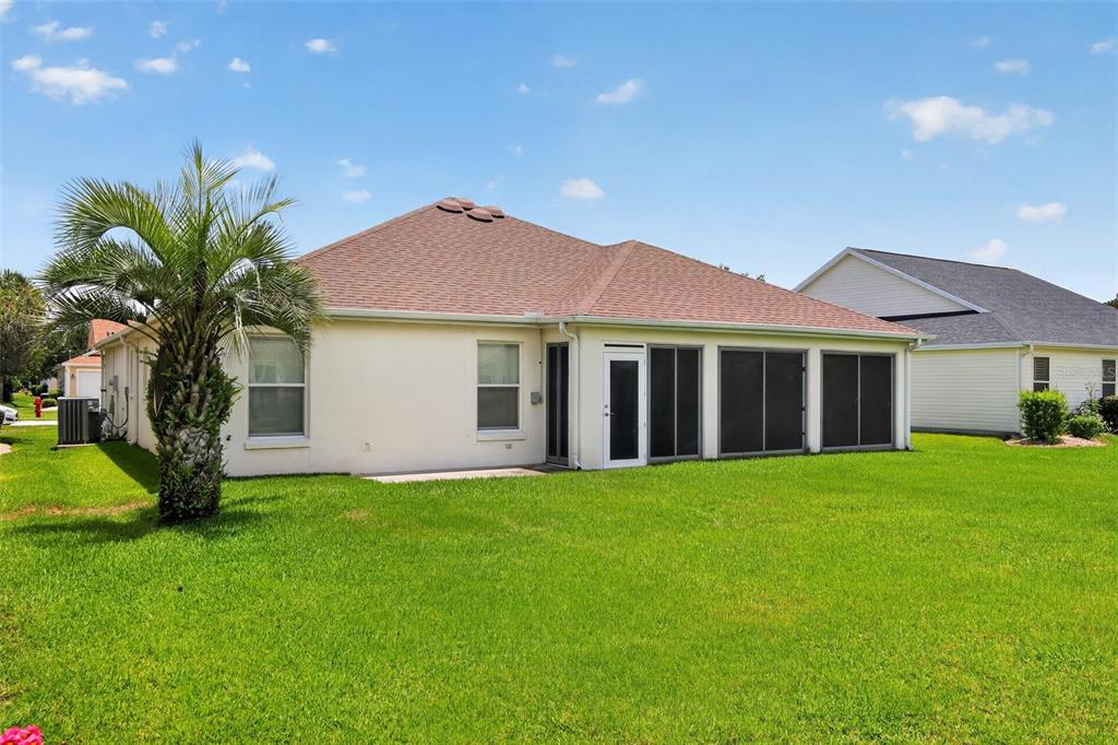 The back exterior of a single-story house with a screened-in porch and a palm tree — 17336 SE 80TH TURNBULL COURT, THE VILLAGES, FL