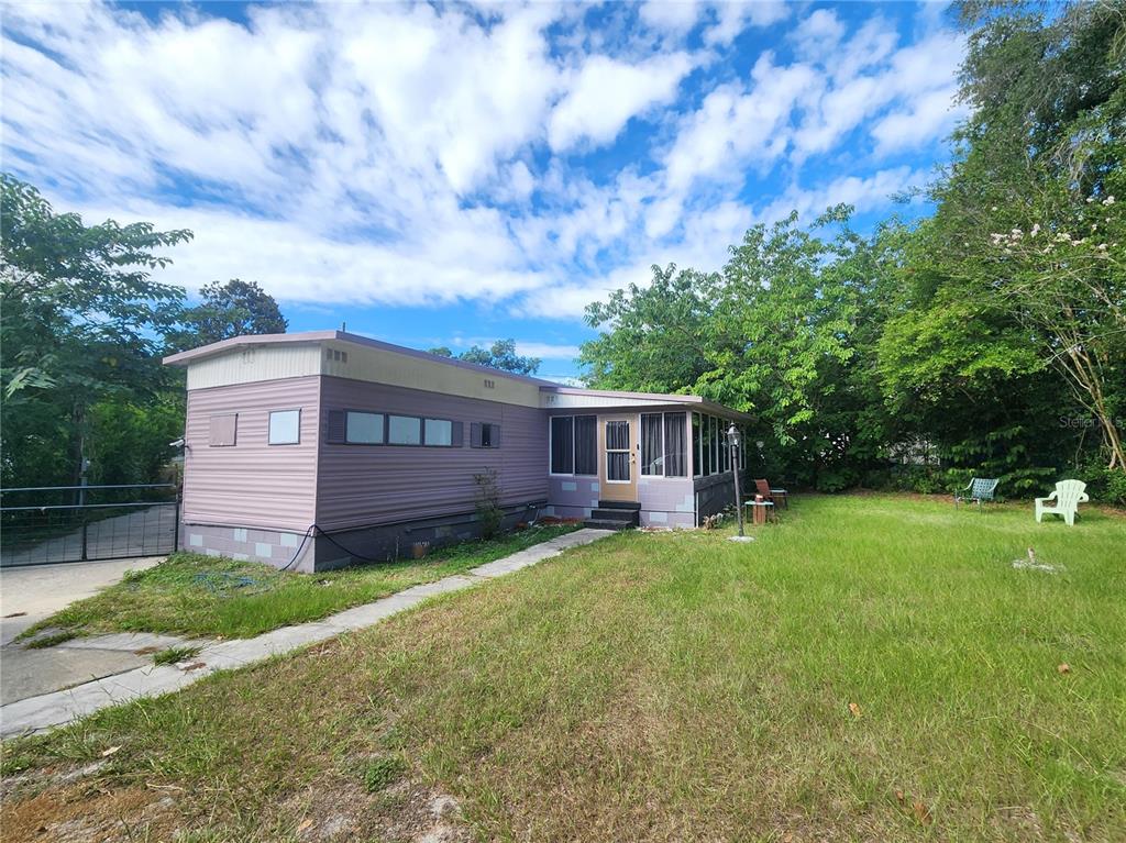 A single-story mobile home with a purple exterior and a screened-in front porch — 900 NW 42ND PLACE, OCALA, FL
