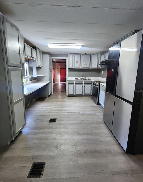 A kitchen features gray cabinets, stainless steel appliances, and light wood-look flooring — 900 NW 42ND PLACE, OCALA, FL