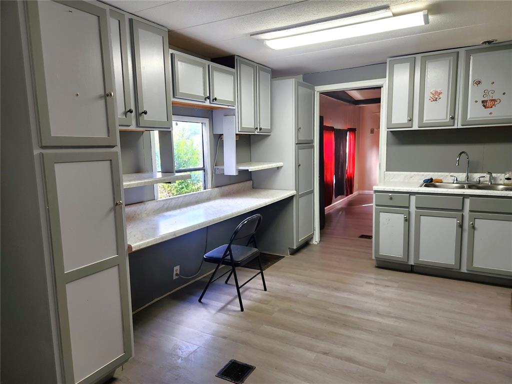 A kitchen features gray cabinets, a long white countertop, a desk area, and light flooring — 900 NW 42ND PLACE, OCALA, FL