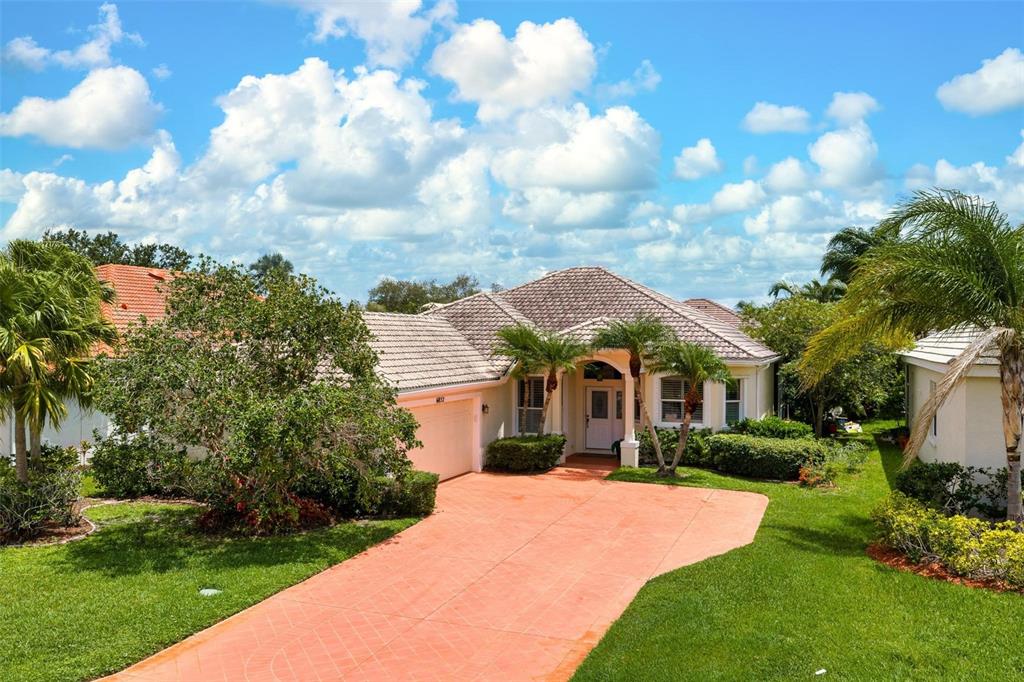 A single-story house with a tiled roof, orange driveway, and palm trees in the yard — 6852 SAGEBRUSH CIRCLE, SARASOTA, FL