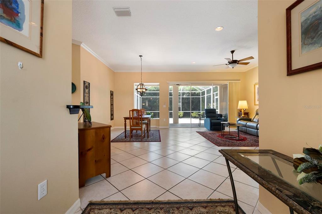 A bright, open-concept living and dining area features tile flooring, neutral walls, and sliding glass doors — 6852 SAGEBRUSH CIRCLE, SARASOTA, FL