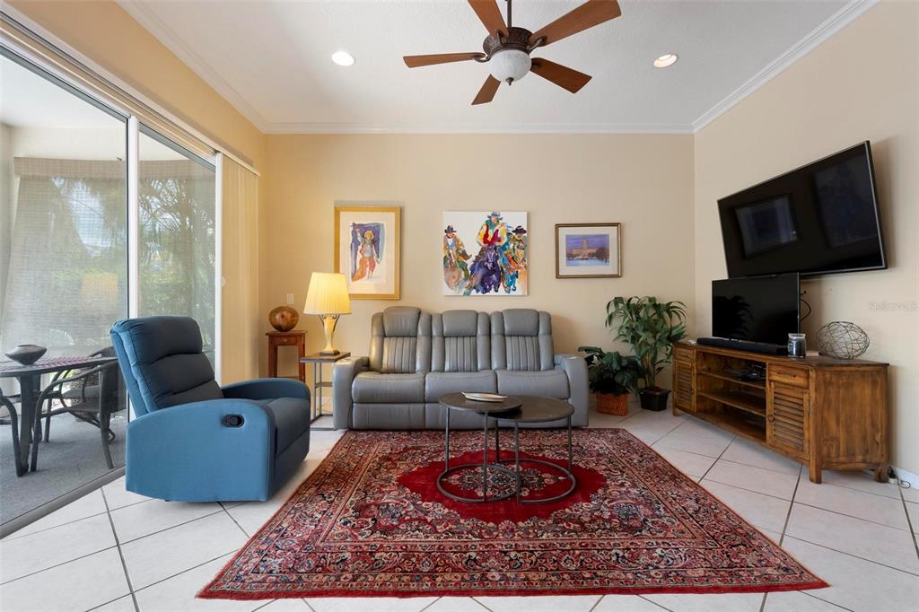 A living room features a grey sofa, a blue recliner, and a red area rug — 6852 SAGEBRUSH CIRCLE, SARASOTA, FL