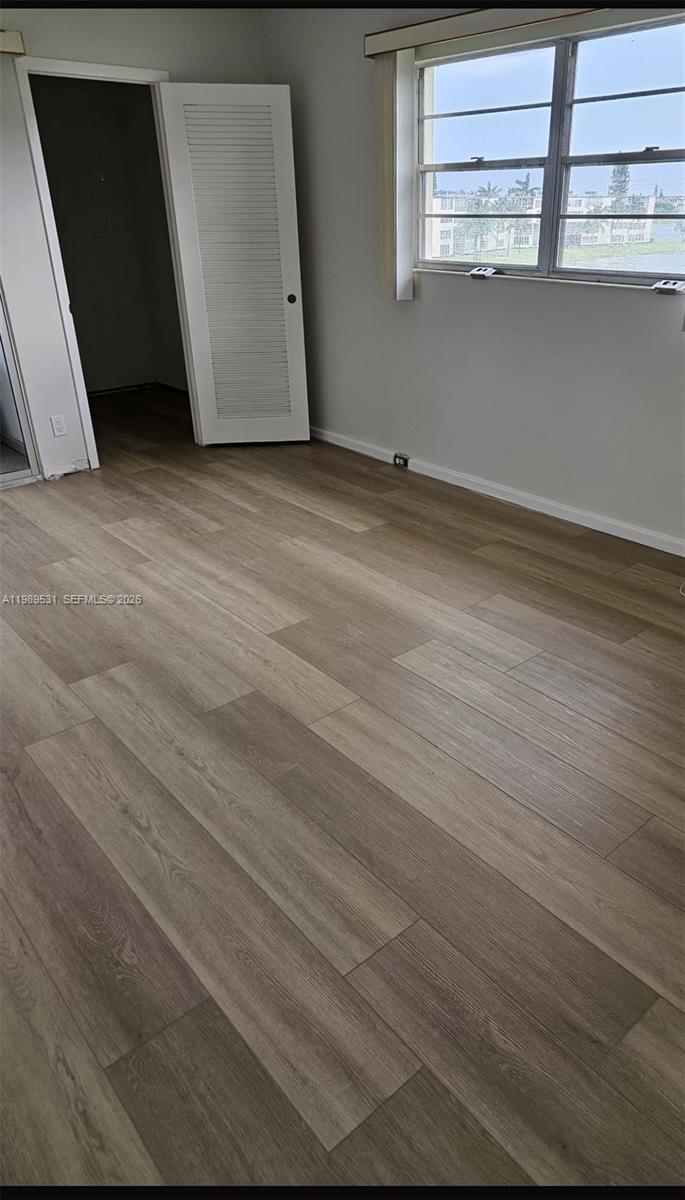 An empty room features light wood-look flooring, gray walls, and a white louvered closet door — 4098 Yarmouth  E # 4098, Boca Raton FL 33434, BOCA RATON, FL