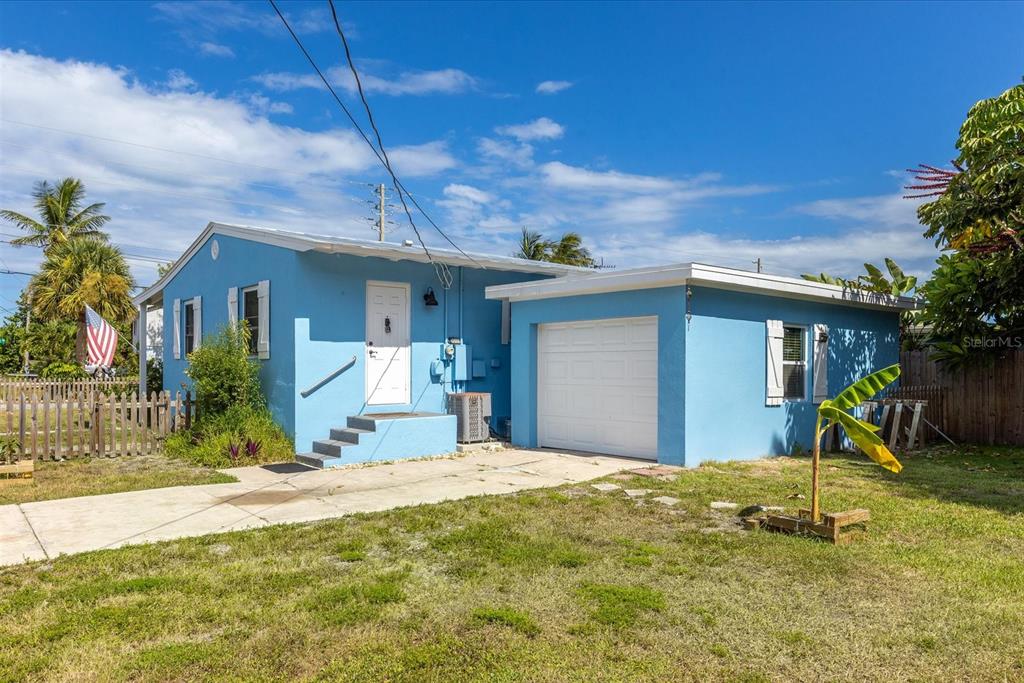 A single-story blue house with a white garage door and a concrete driveway — 301 GRANADA STREET, FORT PIERCE, FL