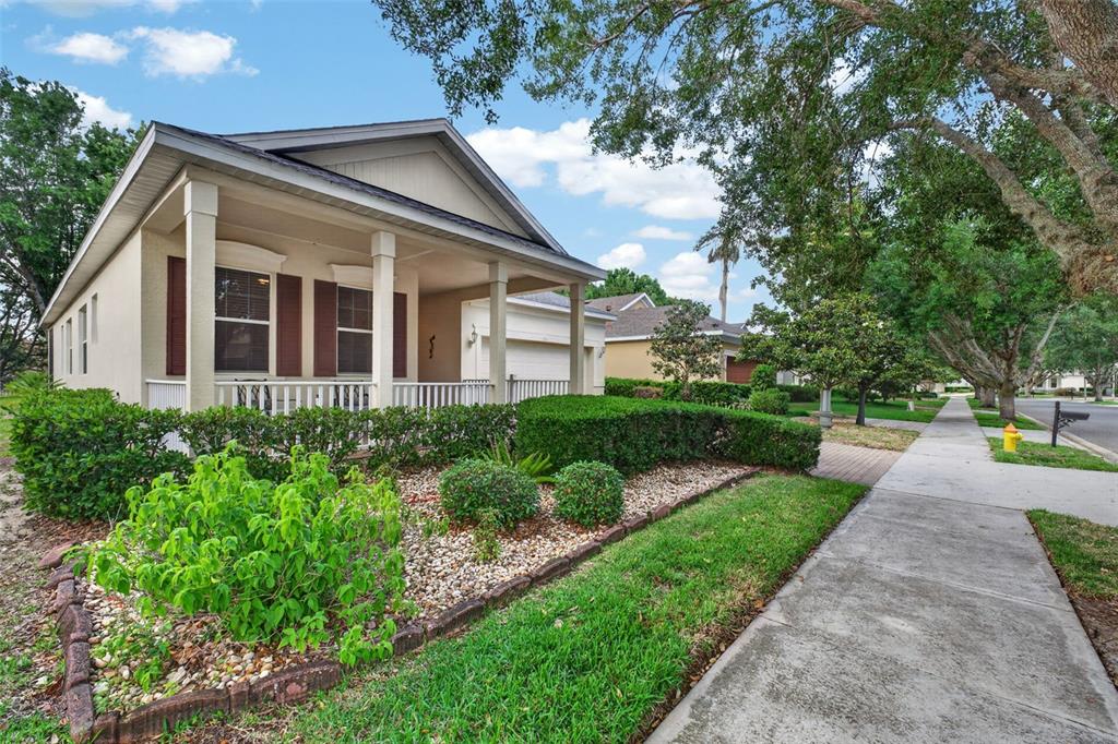 A single-story house with a front porch, tan siding, and landscaped yard along a sidewalk — 111 FLAME VINE WAY, GROVELAND, FL