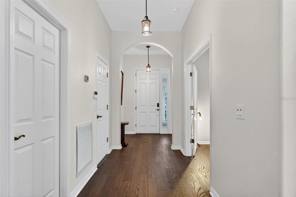 A bright entryway features dark wood flooring, white doors, and two hanging pendant lights — 111 FLAME VINE WAY, GROVELAND, FL