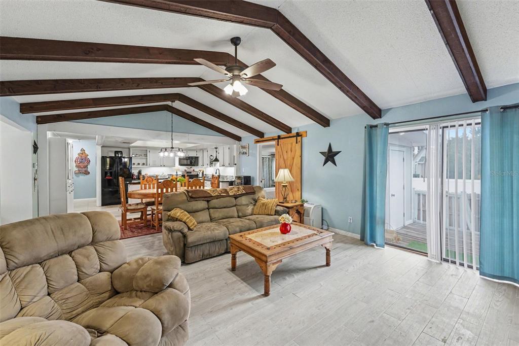 A living room with vaulted ceilings, exposed wooden beams, and light-colored tile flooring — 429 MANOR BOULEVARD, PALM HARBOR, FL